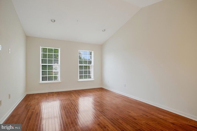 spare room with wood-type flooring and vaulted ceiling