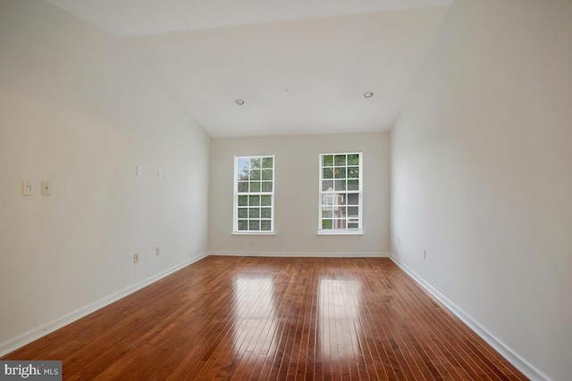 spare room with wood-type flooring and vaulted ceiling