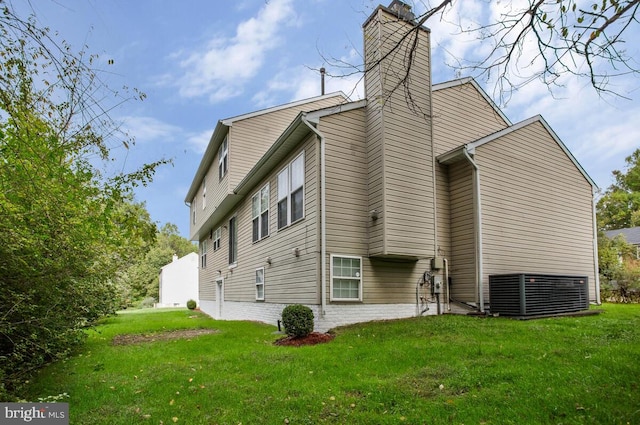 back of property with cooling unit and a yard