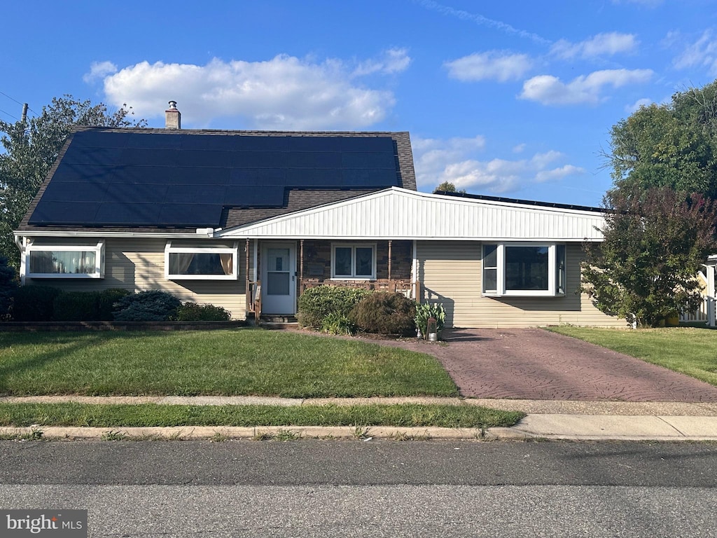 view of front of property featuring a front yard and solar panels