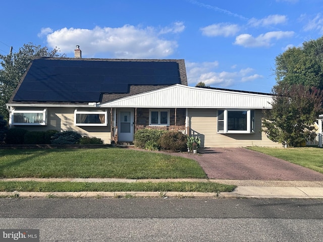 view of front of property featuring solar panels and a front lawn