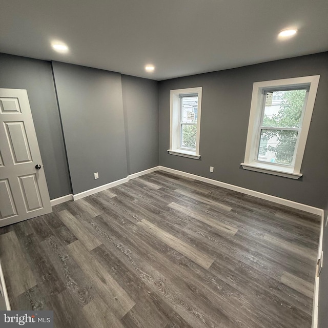 spare room with dark wood-type flooring and plenty of natural light