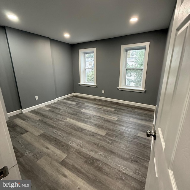 empty room with dark wood-type flooring and a wealth of natural light