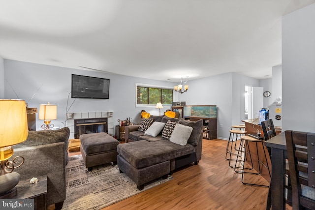 living room featuring hardwood / wood-style floors, a tiled fireplace, and a notable chandelier