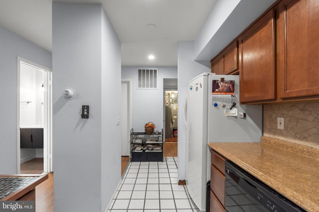 kitchen with white fridge, black dishwasher, light tile patterned floors, and tasteful backsplash