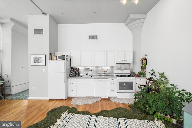 kitchen with white cabinets, sink, tasteful backsplash, white appliances, and light hardwood / wood-style flooring