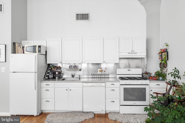 kitchen with decorative backsplash, light hardwood / wood-style floors, white cabinetry, white appliances, and sink