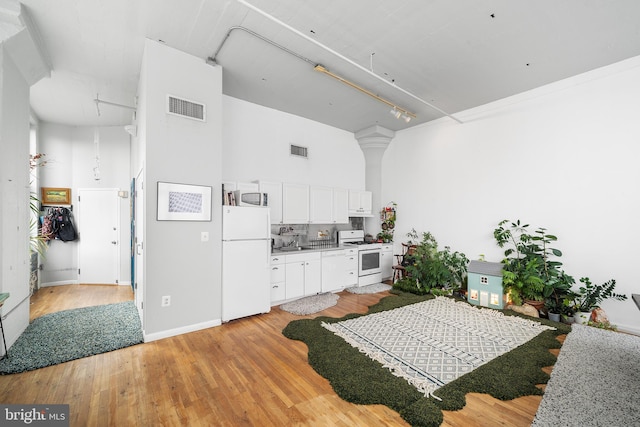 kitchen featuring light hardwood / wood-style floors, white cabinetry, white appliances, a high ceiling, and sink