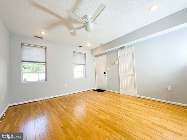 spare room featuring ceiling fan, light hardwood / wood-style flooring, and a textured ceiling