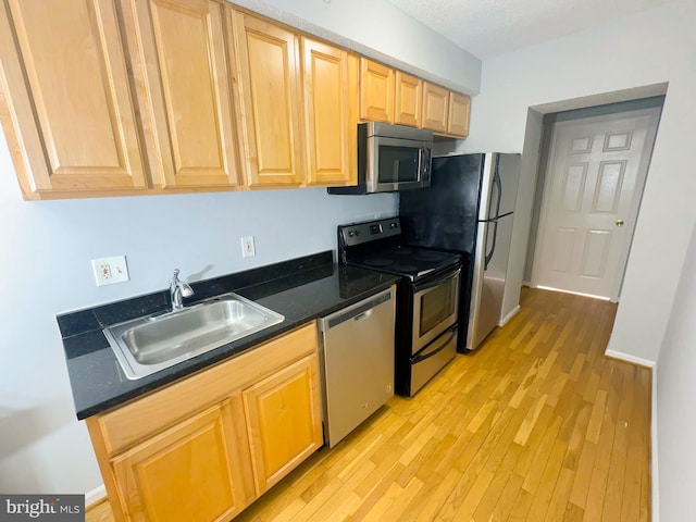 kitchen with stainless steel appliances, light hardwood / wood-style floors, light brown cabinets, and sink