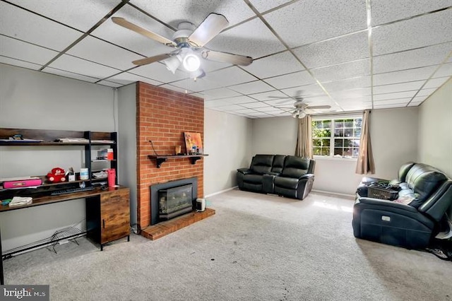 carpeted living room featuring a drop ceiling, a brick fireplace, and ceiling fan