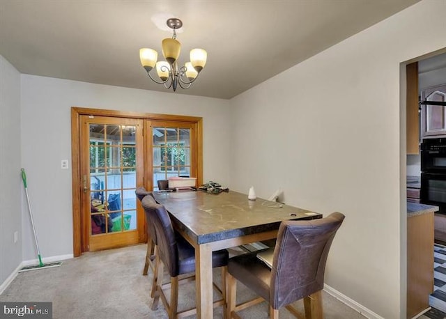 dining area featuring light carpet, an inviting chandelier, and french doors