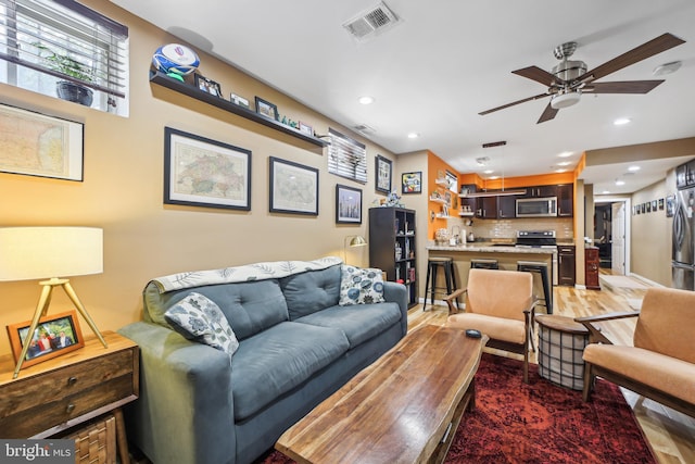 living room with wood-type flooring and ceiling fan