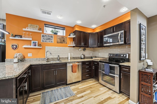 kitchen featuring dark brown cabinets, sink, light hardwood / wood-style flooring, stainless steel appliances, and light stone countertops