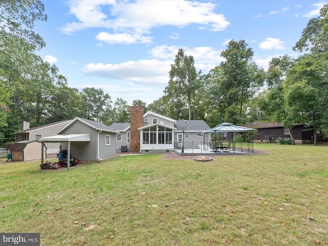 back of house featuring a gazebo, a sunroom, a shed, a lawn, and a patio area