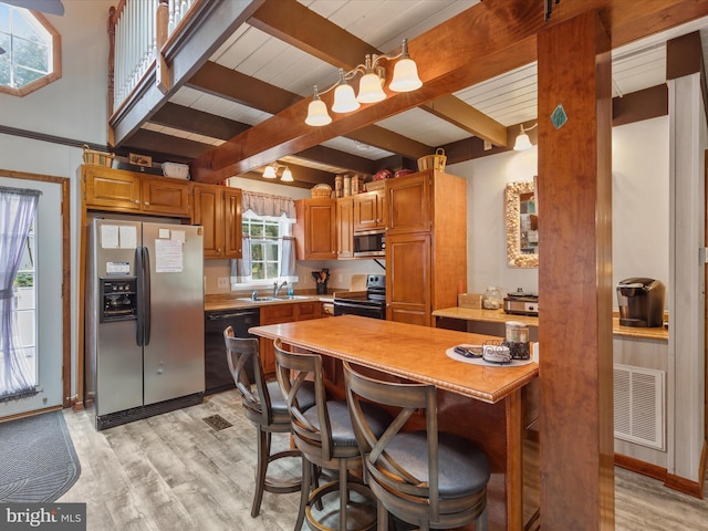 kitchen featuring beamed ceiling, light wood-type flooring, sink, black appliances, and a kitchen bar