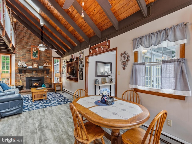 dining area with beamed ceiling, wooden ceiling, hardwood / wood-style floors, a fireplace, and high vaulted ceiling