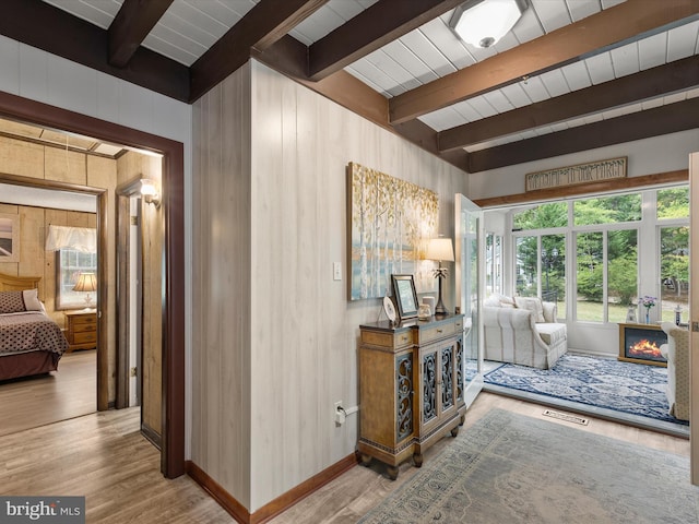 interior space with wooden walls, beam ceiling, and light hardwood / wood-style floors