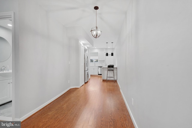 hall featuring a chandelier and light hardwood / wood-style flooring