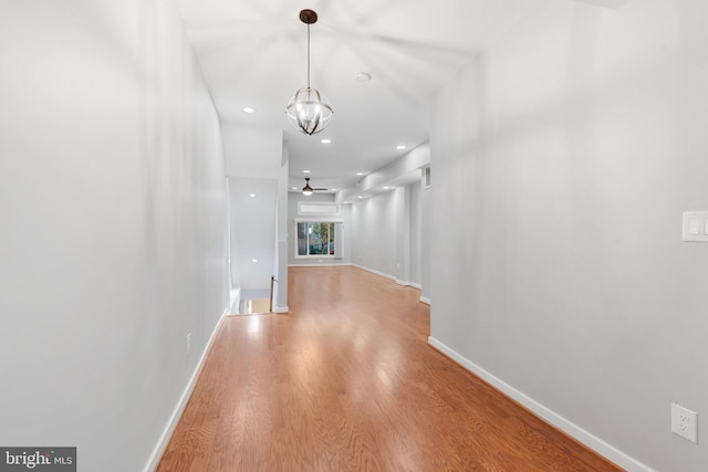 corridor with an inviting chandelier and wood-type flooring