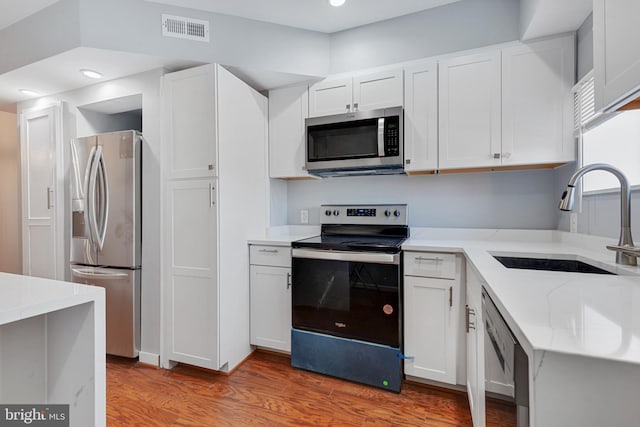 kitchen featuring sink, white cabinetry, light hardwood / wood-style floors, stainless steel appliances, and light stone counters