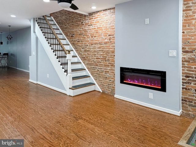 unfurnished living room with brick wall and wood-type flooring