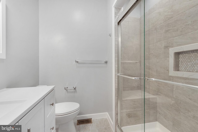 bathroom featuring vanity, toilet, and a shower with shower door