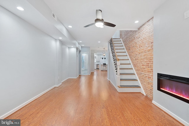 interior space with brick wall, light hardwood / wood-style flooring, and an inviting chandelier