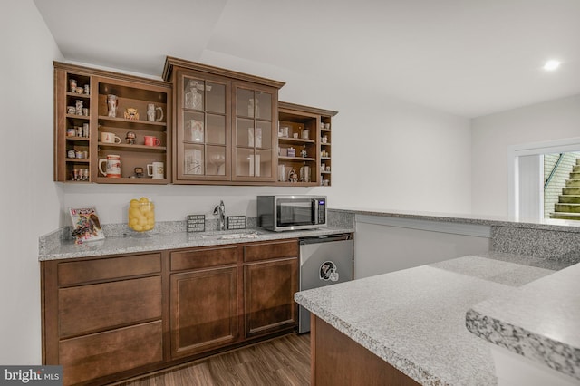 bar with sink, light stone countertops, appliances with stainless steel finishes, and dark hardwood / wood-style flooring