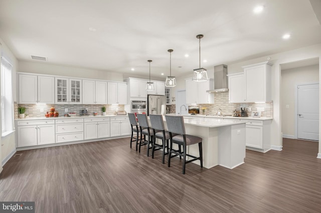 kitchen with appliances with stainless steel finishes, dark hardwood / wood-style floors, white cabinetry, and an island with sink