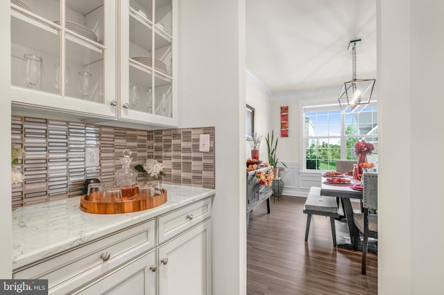 bar featuring white cabinets, dark hardwood / wood-style flooring, backsplash, pendant lighting, and crown molding