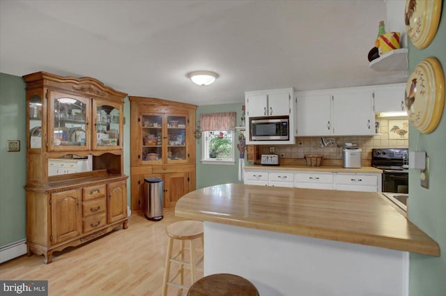 kitchen featuring light hardwood / wood-style floors, stainless steel microwave, white cabinetry, black range with electric cooktop, and backsplash