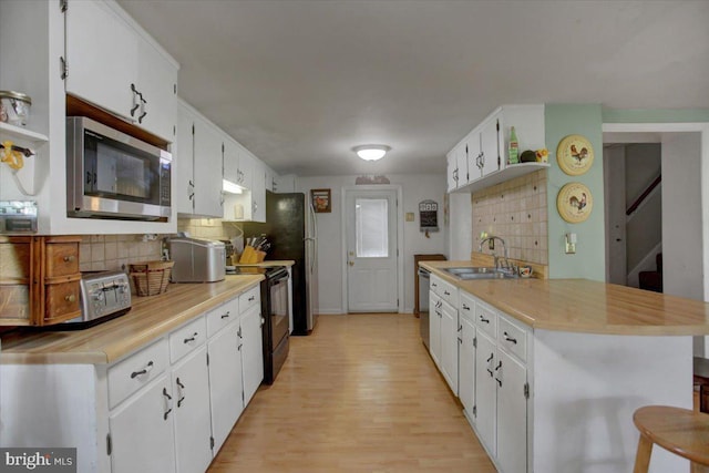 kitchen featuring white cabinets, sink, appliances with stainless steel finishes, light hardwood / wood-style floors, and decorative backsplash