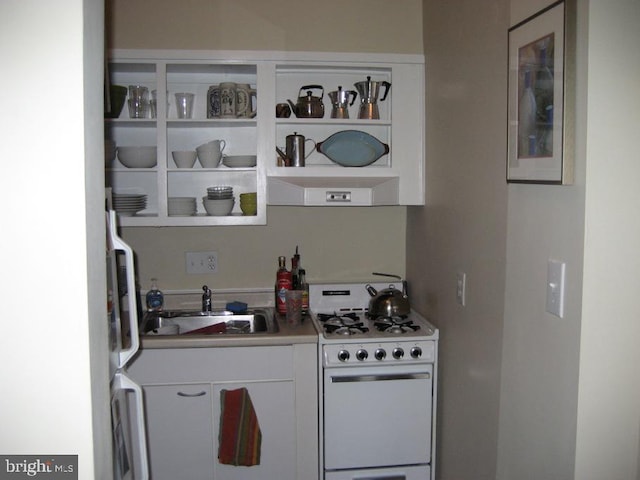 kitchen with sink, white gas stove, and white cabinets