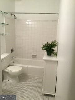 bathroom with toilet, tile patterned floors, and tiled shower / bath