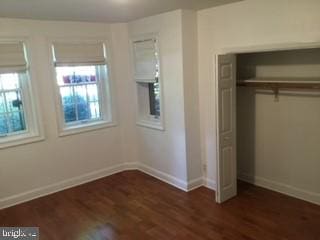 unfurnished bedroom with a closet and dark wood-type flooring