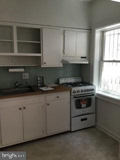 651 Constitution Ave NE, Washington, DC 20002 - kitchen featuring white range with gas stovetop, white cabinetry, a sink, and under cabinet range hood