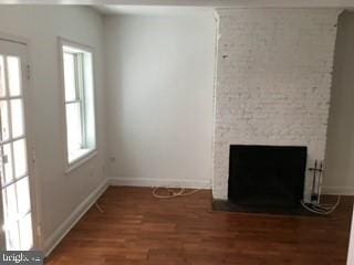 unfurnished living room with dark hardwood / wood-style floors and a large fireplace