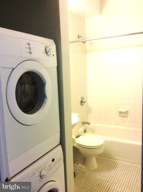 washroom with stacked washer and dryer and tile patterned floors