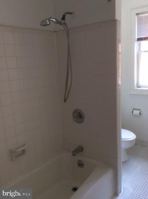 bathroom with toilet, tile patterned floors, and tiled shower / bath