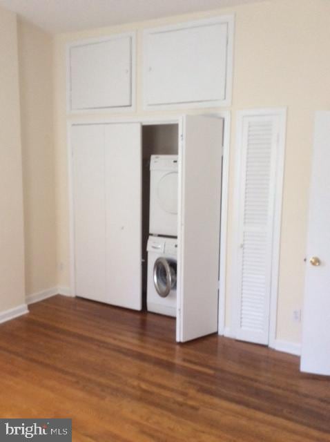 laundry room with dark hardwood / wood-style floors and stacked washer and dryer