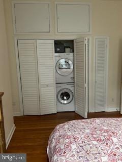 interior space featuring stacked washer / drying machine and dark wood-type flooring