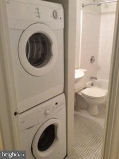 washroom with stacked washer / dryer and tile patterned flooring