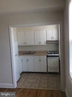 kitchen with sink, white range, white cabinetry, and dark hardwood / wood-style flooring