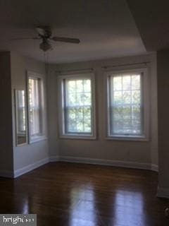 empty room with a wealth of natural light, ceiling fan, and dark wood-type flooring