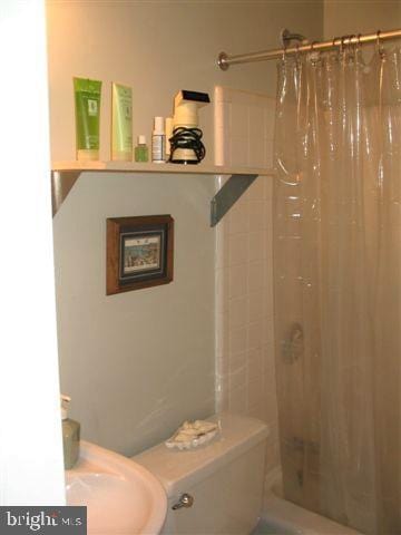 full bathroom with shower / bathtub combination with curtain, sink, and toilet