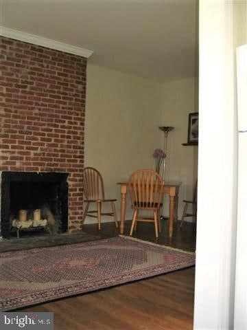 interior space with a fireplace, ornamental molding, and hardwood / wood-style flooring