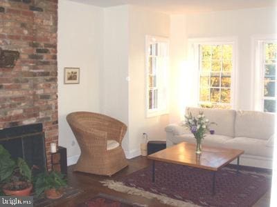 living room with wood-type flooring and a brick fireplace