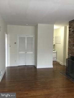 unfurnished living room featuring a brick fireplace and dark hardwood / wood-style floors