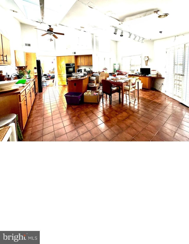 interior space featuring tile patterned flooring, ceiling fan, and brown cabinets